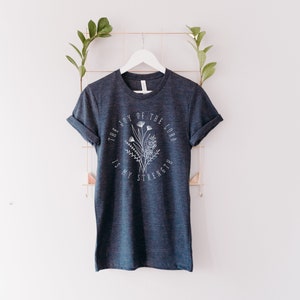 May include: A dark blue t-shirt with a white floral design and the text "The Joy of the Lord is My Strength".
