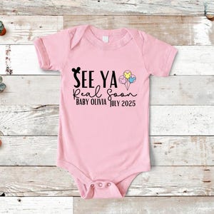 May include: Pink baby onesie with black text that reads "See Ya Real Soon Baby Olivia July 2025" and a black Mickey Mouse head with three colorful balloons with Mickey Mouse heads.