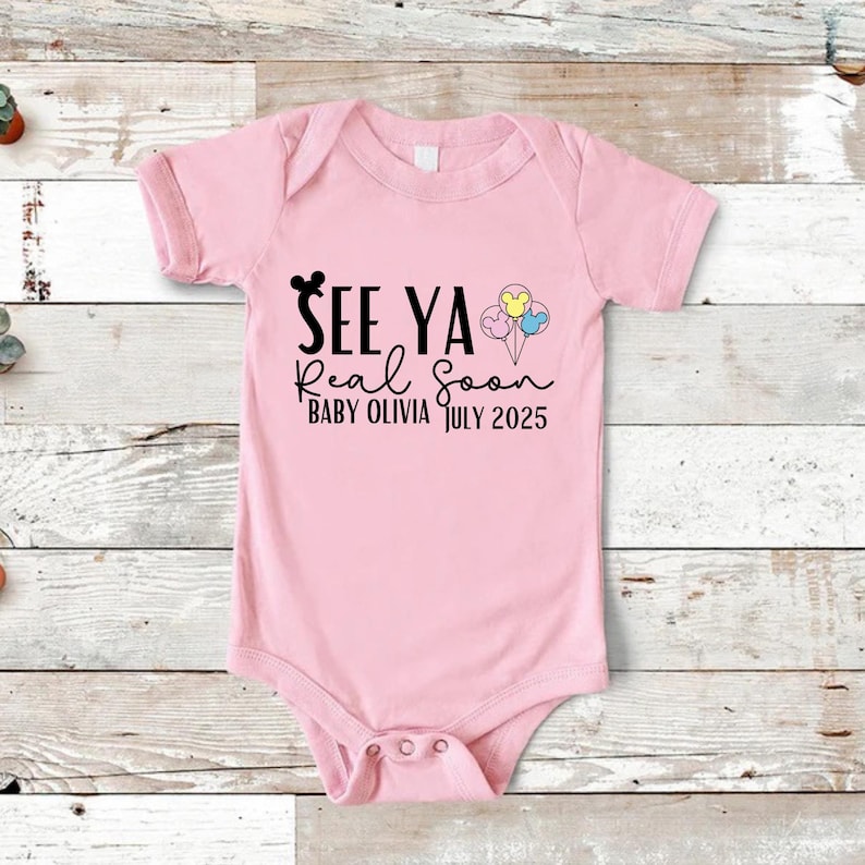 May include: Pink baby onesie with black text that reads "See Ya Real Soon Baby Olivia July 2025" and a black Mickey Mouse head with three colorful balloons with Mickey Mouse heads.