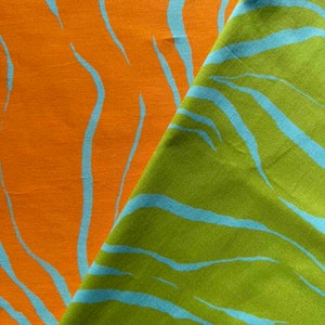 May include: Two pieces of fabric with a zebra stripe pattern. One piece is orange with blue stripes and the other is green with blue stripes.