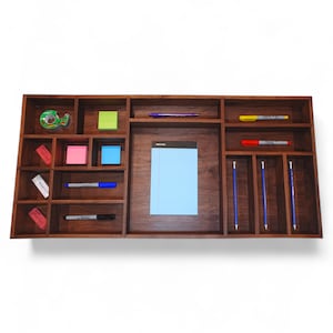 May include: A wooden desk organizer with multiple compartments. The organizer has a light brown finish and includes a notepad, pens, pencils, and sticky notes.