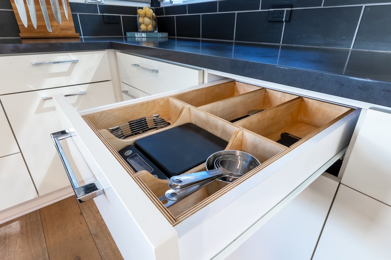 Kitchen Drawer Open showing custom made kitchen drawer insert with organized cooking utensils and tools laid out neatly. Insert is made of 3'8" baltic birch. The image has a modern feel.