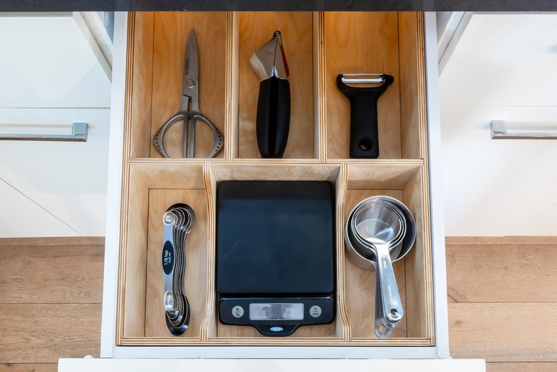 Kitchen Drawer Open showing custom made kitchen drawer insert with organized cooking utensils and tools laid out neatly. Insert is made of 3'8" baltic birch. The image has a modern feel.