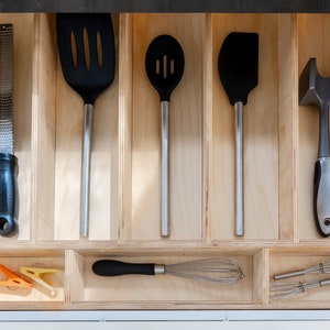 Kitchen Drawer Open showing custom made kitchen drawer insert with organized cooking utensils laid out neatly. Insert is made of 3'8" baltic birch. The image has a modern feel.