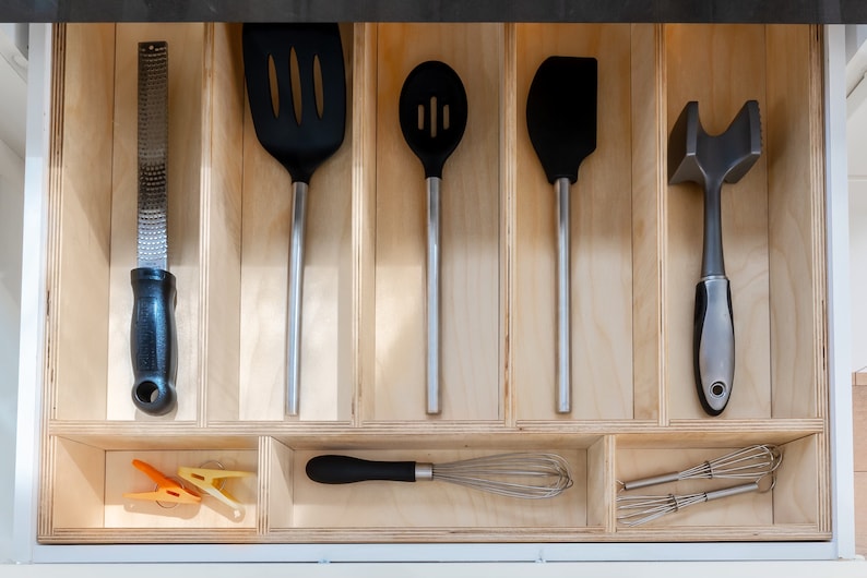 Kitchen Drawer Open showing custom made kitchen drawer insert with organized cooking utensils laid out neatly. Insert is made of 3'8" baltic birch. The image has a modern feel.