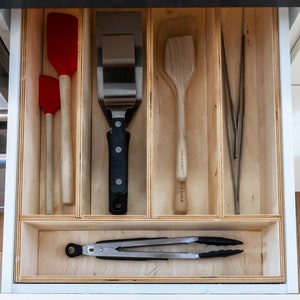 Kitchen Drawer Open showing custom made kitchen drawer insert with organized cooking utensils and tools laid out neatly. Insert is made of 3'8" baltic birch. The image has a modern feel.