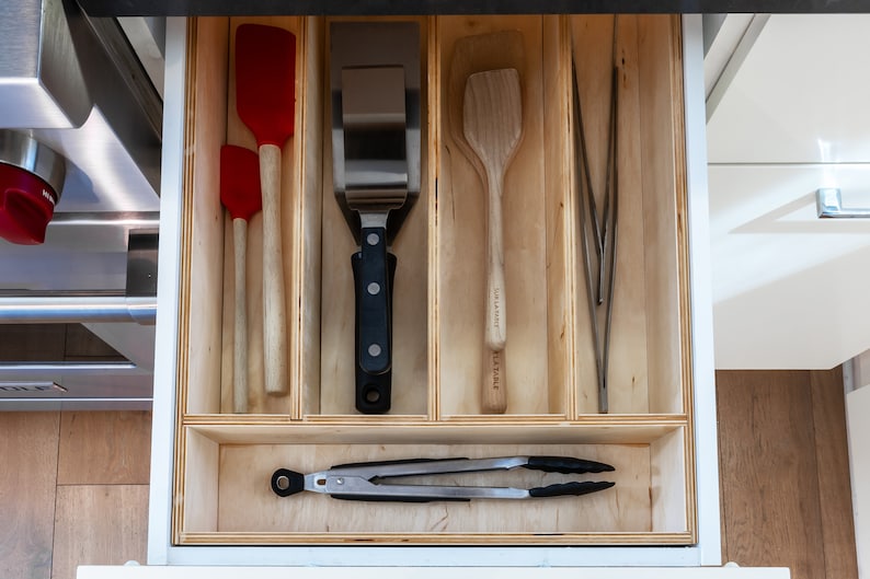 Kitchen Drawer Open showing custom made kitchen drawer insert with organized cooking utensils and tools laid out neatly. Insert is made of 3'8" baltic birch. The image has a modern feel.