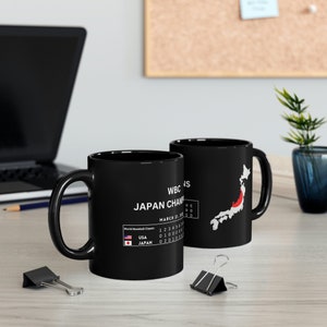 Könnte beinhalten: Schwarze Keramiktasse mit einer weißen Grafik der Umrisse Japans und dem Text "WBC '23 JAPAN CHAMPIONS" mit dem Ergebnis des Spiels USA gegen Japan. Die Tasse enthält auch den Text "World Baseball Classic" und "MARCH 21, 2023".