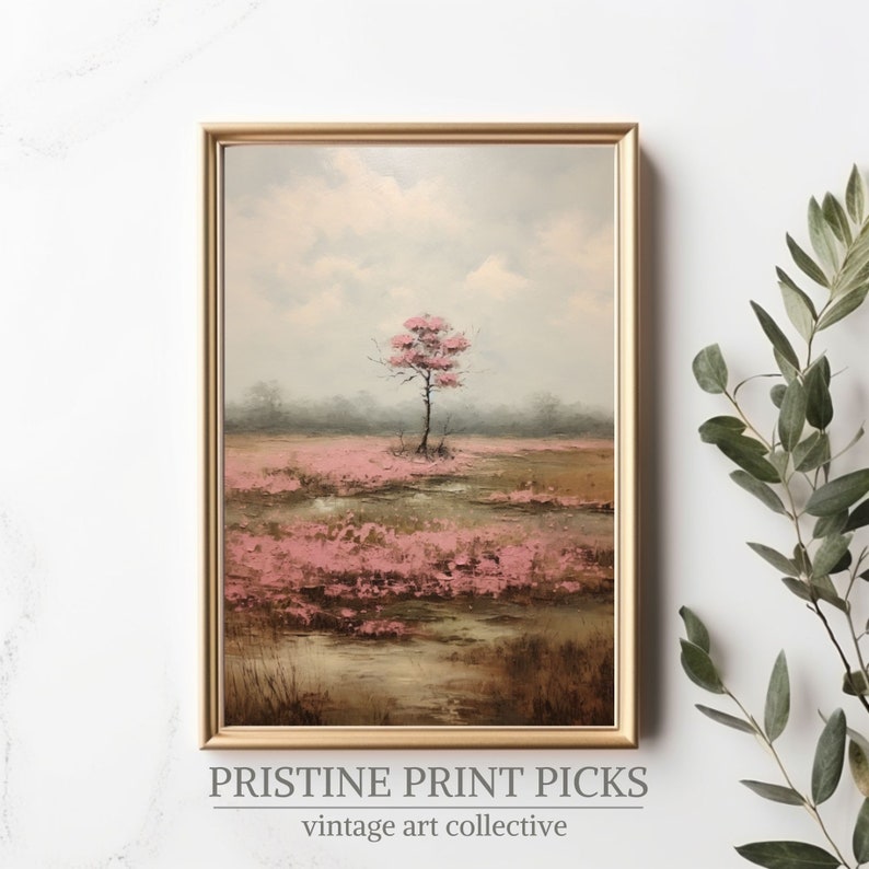 May include: A framed landscape painting featuring a solitary tree with pink blossoms in a field of pink flowers. The artwork has a gold frame and a soft, muted color palette. The text "PRISTINE PRINT PICKS vintage art collective" is at the bottom.