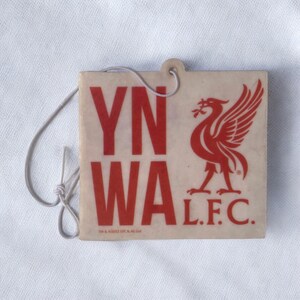 May include: A white car air freshener with a red Liverpool Football Club logo, a red bird, and the text "YNWA L.F.C."