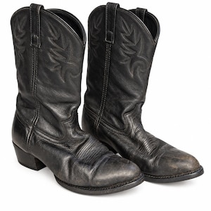 Puede incluir: Un par de botas vaqueras de cuero negro con acabado texturizado, punta puntiaguda y tacón de bloque. La caña de cada bota está decorada con patrones de costura tonales e incluye dos tiradores en la parte superior para facilitar su uso.