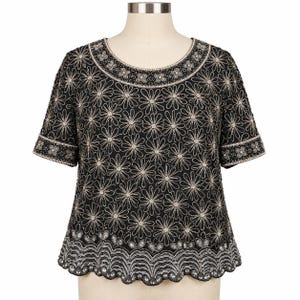 May include: A black short-sleeved top featuring an all-over silver beaded daisy pattern. The garment has a round neckline with a beaded border, matching beaded sleeve cuffs, and a scalloped hemline adorned with intricate silver beadwork.