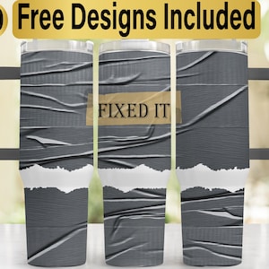 May include: A stainless steel tumbler with a gray duct tape design and the text "FIXED IT" on a brown tape strip. The tumbler has a lid and a handle.
