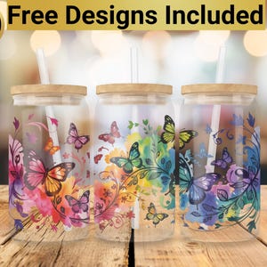 May include: Three clear glass tumblers with bamboo lids and straws. Each tumbler features a different watercolor design with butterflies and floral elements in shades of pink, purple, blue, green, and yellow.