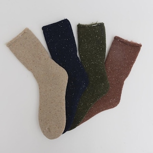May include: Four pairs of speckled knit socks in shades of tan, navy blue, olive green, and brown. The socks are displayed together, highlighting their different colours and textures. The socks appear to be made of a warm, comfortable material.