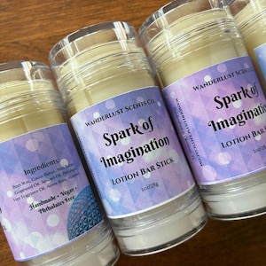 May include: Several lotion bar sticks with clear plastic tops and labels that read "Spark of Imagination." The labels are purple and white with the brand name "Wanderlust Scents Co." and ingredient information. Each stick is 1 oz/28g.
