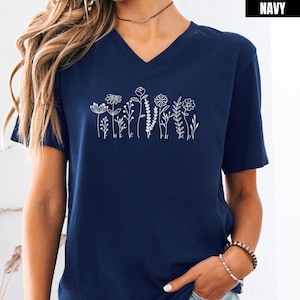 Könnte beinhalten: Ein marineblaues V-Ausschnitt-T-Shirt mit einem weißen Umriss einer Reihe von Blumen und Blättern.