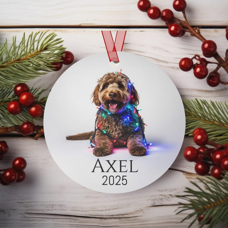 Round Christmas ornament with a labradoodle wrapped in colorful Christmas lights.  Axel and 2025 are at the bottom.  Name and year can be personalized.