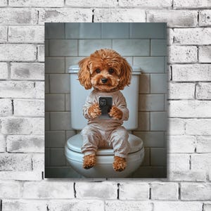 May include: A brown and white poodle dog wearing pajamas sits on a white toilet seat and holds a smartphone in its paws.