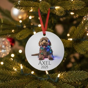 Round Christmas ornament with a labradoodle wrapped in colorful Christmas lights.  Axel and 2024 are at the bottom.  Name and year can be personalized.