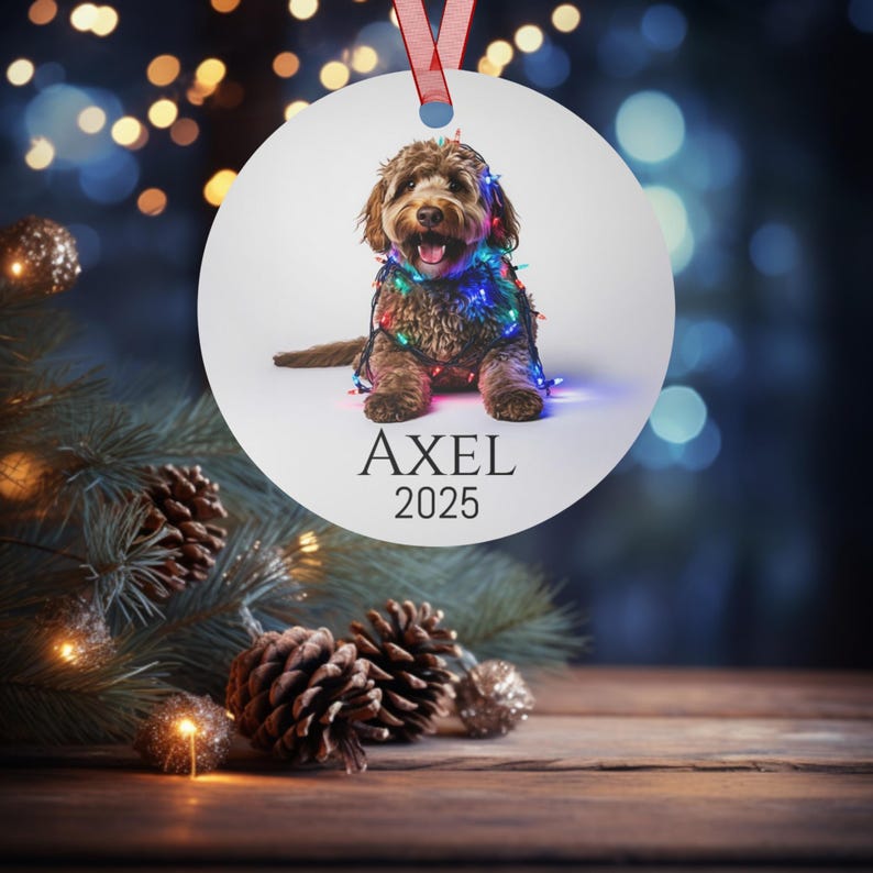 Round Christmas ornament with a labradoodle wrapped in colorful Christmas lights.  Axel and 2025 are at the bottom.  Name and year can be personalized.