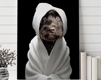 以下が含まれることがあります： 白いタオルに包まれた黒い犬が、真顔でカメラを見つめている。