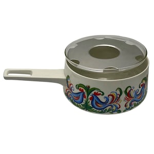 Könnte beinhalten: Weiße Keramik-Fondue-Topf mit Glasdeckel und Metalleinsatz. Der Topf hat ein farbenfrohes Hahnendesign mit roten, blauen, gelben und grünen Akzenten.