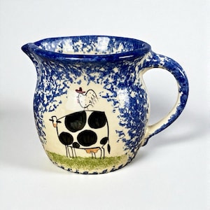 May include: A white ceramic mug with a black handle and the text "But First, Coffee" in a black, handwritten-style font. The mug is on a white surface.