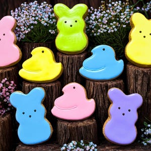 May include: An assortment of colorful Easter-themed cookies, including pink and purple bunnies, and yellow, blue, and pink chicks. The cookies are arranged on wooden platforms with floral accents, creating a festive display.