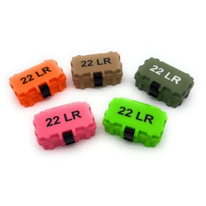 Op de afbeelding: Vijf kleine, rechthoekige containers in verschillende kleuren: oranje, bruin, groen, roze en limoengroen. Elke container heeft de tekst "22 LR" in zwarte letters. Een zwarte band is zichtbaar aan de voorkant van elke container.