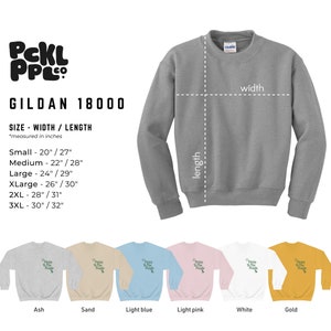 Puede incluir: Una sudadera Gildan 18000 de color gris ceniza con el texto "PCKL PPL" en verde. La sudadera est&aacute; disponible en 10 colores: ceniza, arena, azul claro, rosa claro, blanco, dorado, azul marino, negro, rojo y gris jaspeado. La tabla de tallas muestra el ancho y la longitud de la sudadera en pulgadas.