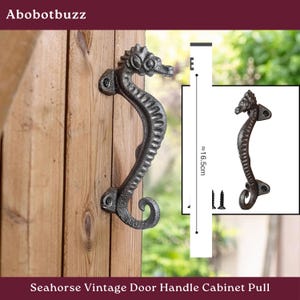 May include: A seahorse-shaped, vintage-style door handle in a dark, textured finish. The handle, approximately 6.5 inches long, is mounted on a wooden door. The design includes a seahorse head and a curved body, with mounting hardware visible.