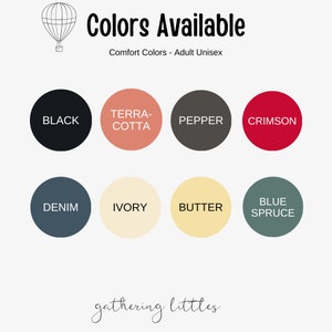 May include: Image displaying a color chart for Comfort Colors adult unisex apparel. The chart features eight circular color swatches: black, terracotta, pepper, crimson, denim, ivory, butter, and blue spruce. A hot air balloon illustration is in the upper left corner.