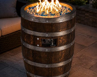 Könnte beinhalten: Eine zylindrische Feuerstelle aus einem dunkelbraunen Holzfass mit verwitterten silbernen Metallbändern. Die Oberseite enthält ein Bett aus blauen und klaren Glasperlen mit aktiven orangefarbenen Flammen. Ein Bedienfeld ist an der Seite sichtbar.