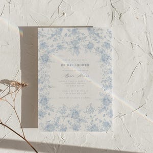 K&ouml;nnte beinhalten: Eine blaue und wei&szlig;e, floral gemusterte Einladung zu einer Bridal Shower mit dem Text "Bitte nehmen Sie an unserer Bridal Shower zu Ehren der Braut,  [Name der Braut], teil. Sonntag, 1. Juli 2018 um 11:00 Uhr, Roundtop Terrace, 123 Ridge Rd, NY. Bitte melden Sie sich bis zum 20. Mai bei Sarah Rae unter 123-456-7890 an. Geschenkeliste bei Crate & Barrel."