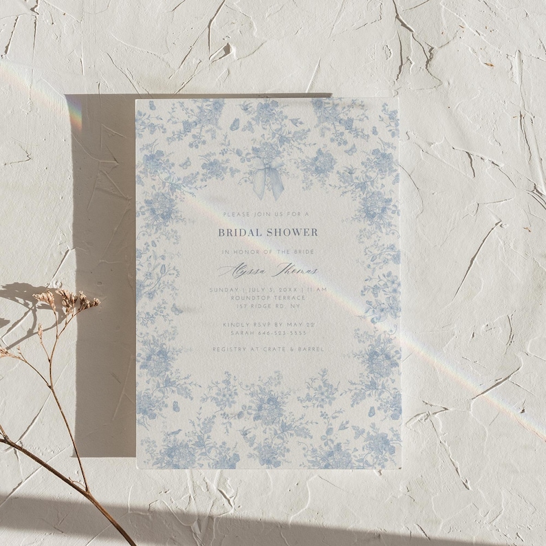 K&ouml;nnte beinhalten: Eine blaue und wei&szlig;e, floral gemusterte Einladung zu einer Bridal Shower mit dem Text "Bitte nehmen Sie an unserer Bridal Shower zu Ehren der Braut,  [Name der Braut], teil. Sonntag, 1. Juli 2018 um 11:00 Uhr, Roundtop Terrace, 123 Ridge Rd, NY. Bitte melden Sie sich bis zum 20. Mai bei Sarah Rae unter 123-456-7890 an. Geschenkeliste bei Crate & Barrel."
