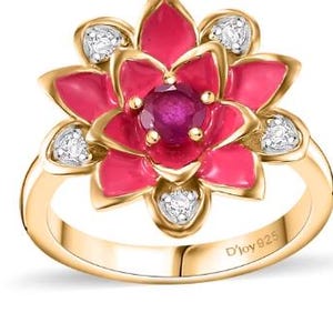 Puede incluir: Un anillo de oro con un diseño de flor de esmalte rosa y piedras preciosas transparentes. El anillo está marcado con "D'Joy 925".