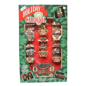 May include: A boxed holiday carousel set with six carousel figures and a circus organ. The box features the text "Holiday Carousel" and "21 Favorite Christmas Carols". The carousel figures include animals and are displayed on a red background.