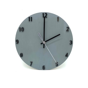 May include: A light blue round clock with black numbers and hands. The clock face has a subtle texture.