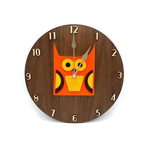 May include: A round wooden clock with an orange owl design. The clock face has gold numbers and the hands are silver. The owl has yellow eyes and a yellow beak.