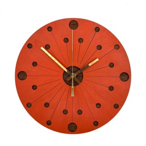 May include: A round, orange clock with black dots and gold hands. The clock face has a sunburst design.