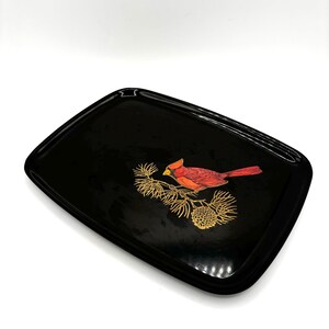 May include: Black rectangular tray with a gold and red cardinal bird design. The bird is perched on a pine branch with pine cones.