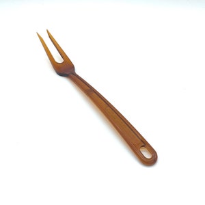 Peut inclure: Une fourchette en plastique marron avec un long manche. La fourchette a deux dents et un manche arrondi.