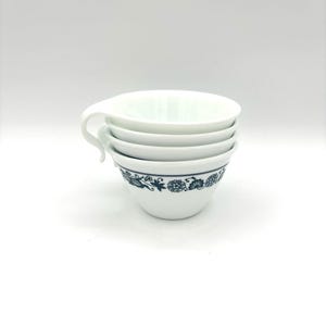 May include: Four white ceramic teacups with a blue floral pattern stacked on top of each other.