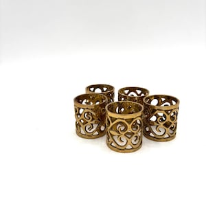 May include: A white ceramic mug with a black handle and the text "But First, Coffee" in a bold, black font. The mug is set against a blurred background, suggesting a cozy setting.