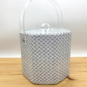 May include: A white ice bucket with a blue geometric pattern and a clear plastic handle and lid.