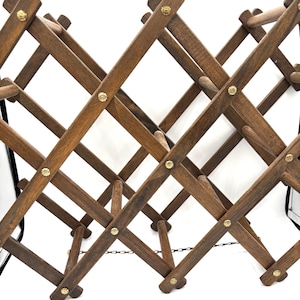 Peut inclure: Un porte-bouteilles en bois avec un motif en losange et des accents en laiton. Le porte-bouteilles est en bois brun foncé et est relié par une chaîne.