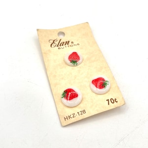May include: Three strawberry-themed buttons on a vintage Elan Buttons card. The buttons feature a red strawberry design with green leaves on a white background. The card has the text "Elan Buttons" and "HKZ-128".