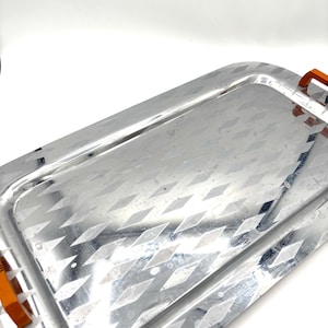 May include: A silver serving tray with a diamond pattern and orange plastic handles.