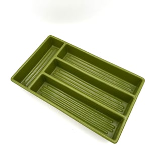 May include: Olive green plastic cutlery tray with multiple compartments. The tray has a rectangular shape with a series of long, narrow slots for organizing utensils. The interior of each slot has a ridged texture.
